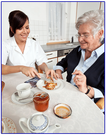 A woman and an older woman sit at a table, sharing a meal from a plate in front of them.